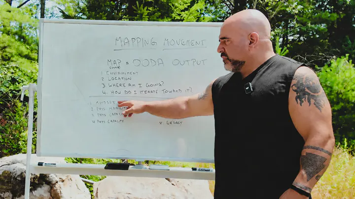 Master Chim pointing at a whiteboard outdoors