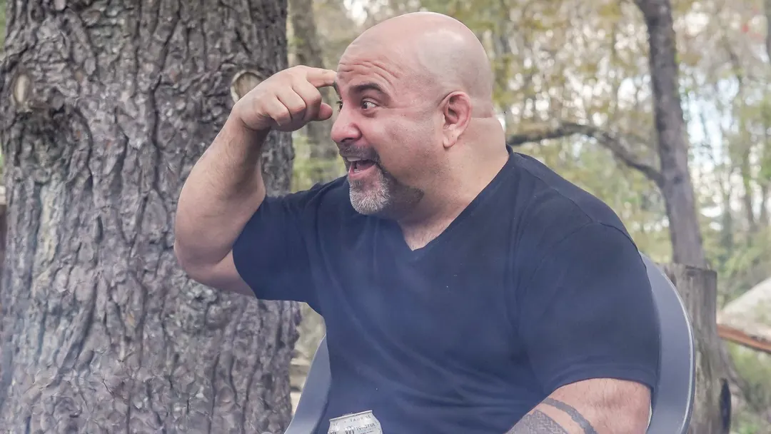 Master Chim seated outdoors, pointing to his head