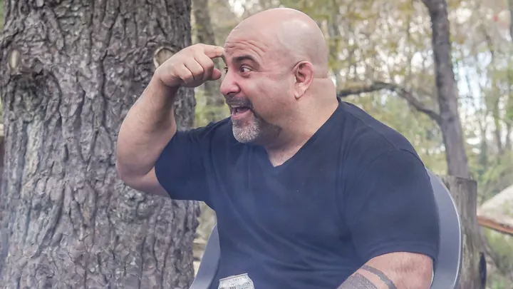 Master Chim seated outdoors, pointing to his head